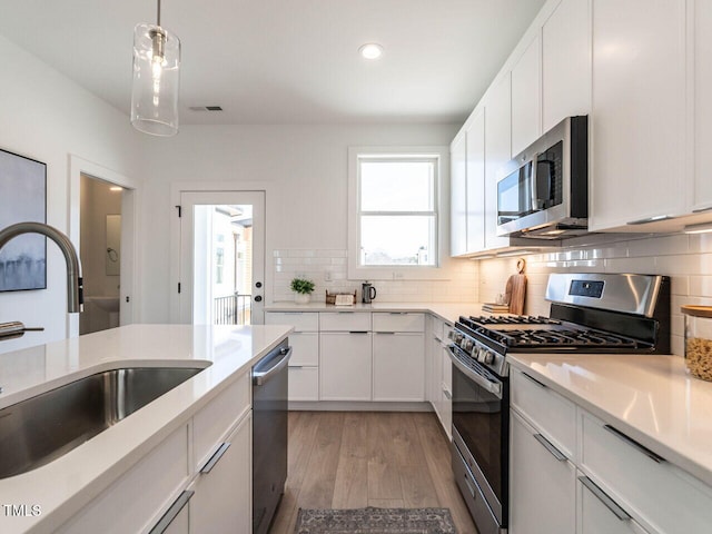 kitchen featuring a sink, stainless steel appliances, tasteful backsplash, and light countertops