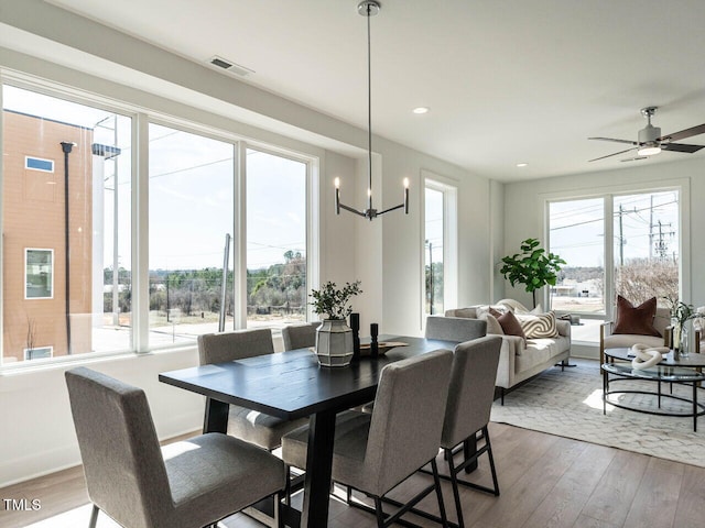 dining room with wood finished floors, visible vents, baseboards, recessed lighting, and ceiling fan with notable chandelier