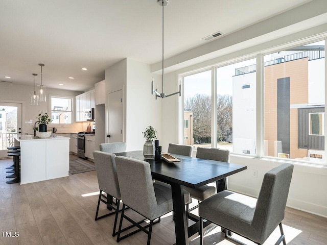 dining room featuring visible vents, light wood finished floors, baseboards, recessed lighting, and a notable chandelier