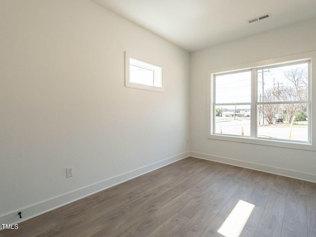 empty room featuring visible vents, baseboards, and wood finished floors