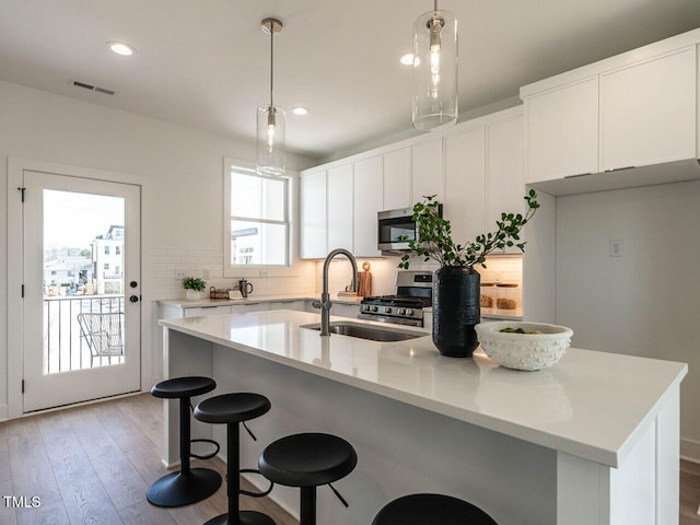 kitchen with light countertops, decorative backsplash, appliances with stainless steel finishes, a kitchen breakfast bar, and a sink