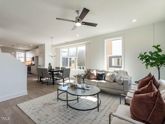 living area with recessed lighting, ceiling fan with notable chandelier, and light wood-style floors