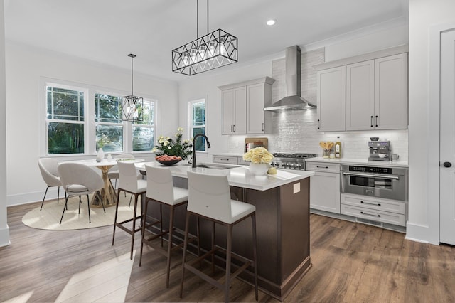 kitchen with pendant lighting, wall chimney range hood, sink, dark hardwood / wood-style flooring, and stainless steel appliances