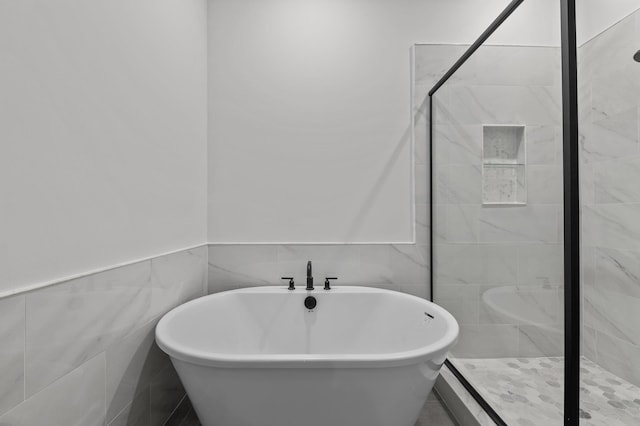 bathroom featuring independent shower and bath and tile walls