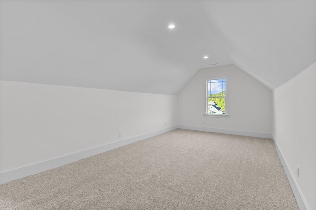 additional living space with light carpet and vaulted ceiling