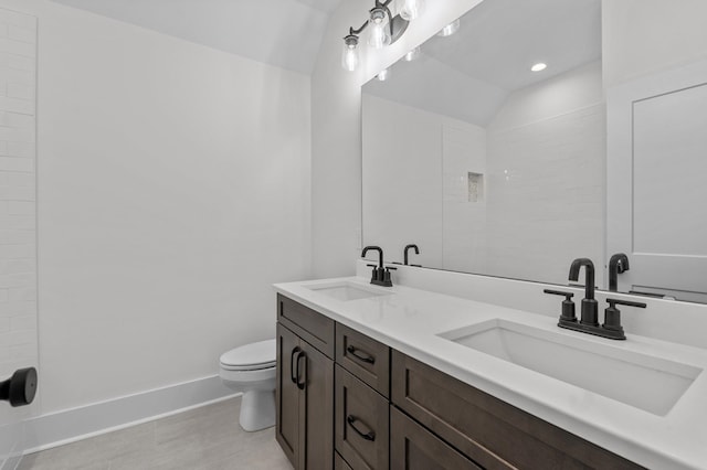 bathroom featuring tile patterned floors, vanity, vaulted ceiling, and toilet