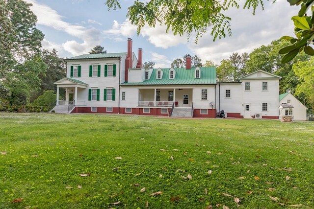 rear view of property featuring a lawn and a porch