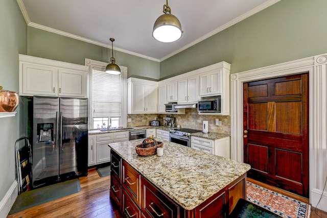 kitchen with pendant lighting, a kitchen island, tasteful backsplash, dark wood-type flooring, and appliances with stainless steel finishes