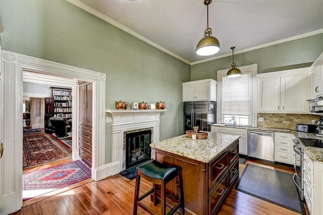 kitchen featuring dark hardwood / wood-style flooring, decorative light fixtures, appliances with stainless steel finishes, a kitchen bar, and light stone countertops