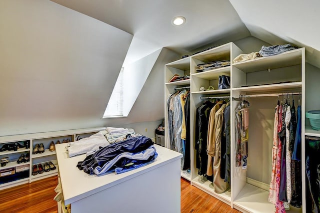 walk in closet featuring vaulted ceiling with skylight and light hardwood / wood-style flooring