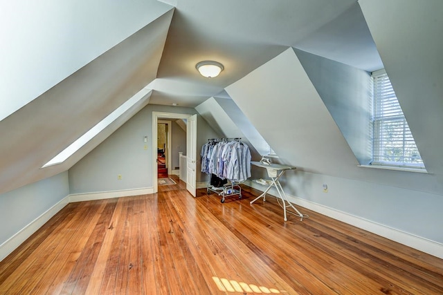 bonus room featuring lofted ceiling with skylight and light hardwood / wood-style flooring