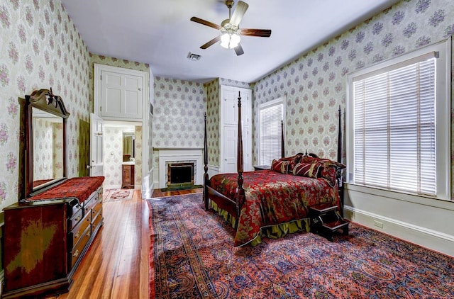 bedroom with ceiling fan, wood-type flooring, and multiple windows