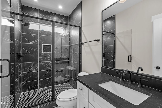 bathroom with toilet, a shower with shower door, and vanity with extensive cabinet space