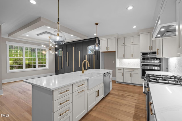 kitchen with a chandelier, a center island with sink, light wood-type flooring, pendant lighting, and sink