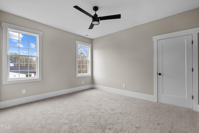 unfurnished room featuring light carpet, ceiling fan, and a wealth of natural light