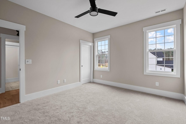 carpeted spare room with plenty of natural light and ceiling fan