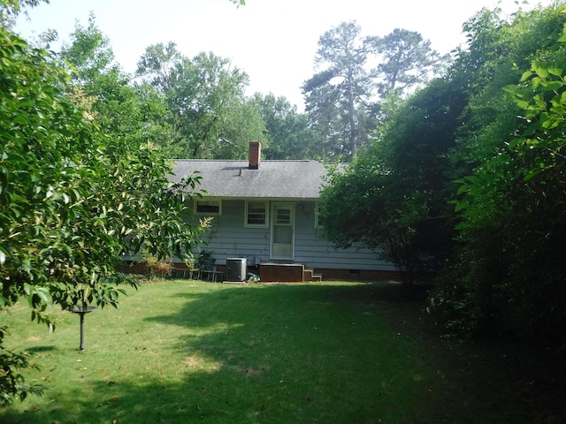 back of property featuring central AC unit and a lawn