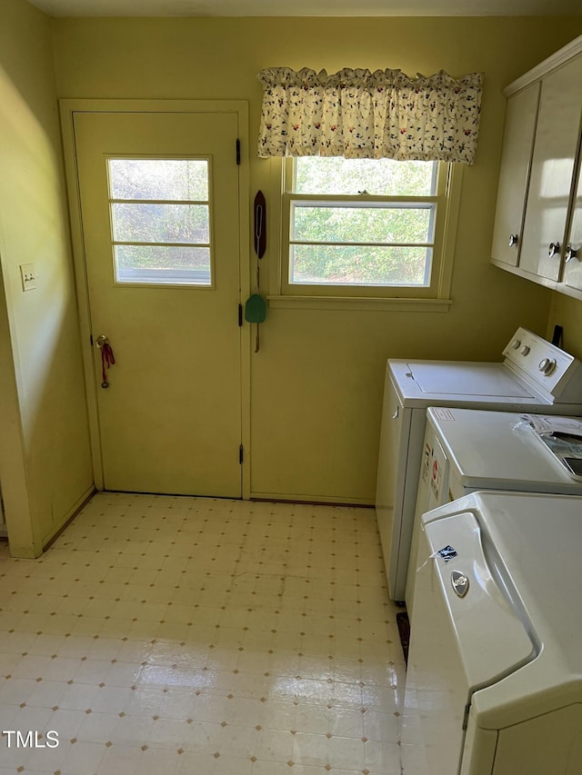 clothes washing area with cabinets and washer and dryer