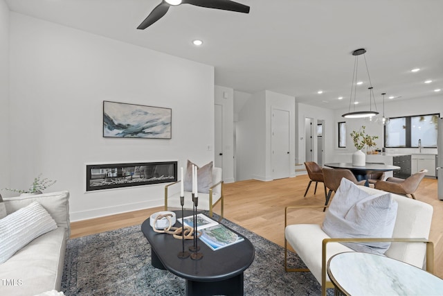 living room with ceiling fan and light hardwood / wood-style flooring