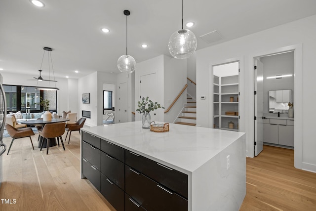 kitchen featuring decorative light fixtures, a kitchen island, ceiling fan, and light hardwood / wood-style flooring