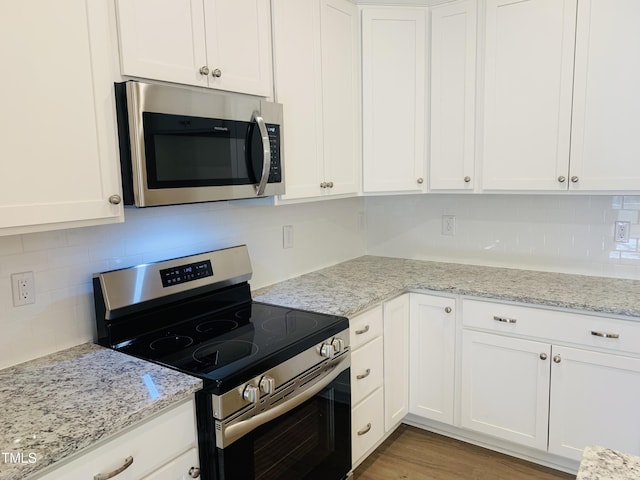 kitchen with white cabinetry, light stone counters, tasteful backsplash, and appliances with stainless steel finishes