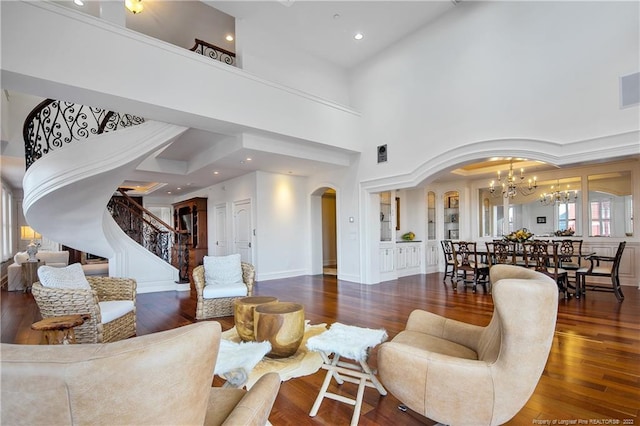 living room with a towering ceiling, a notable chandelier, and dark hardwood / wood-style flooring