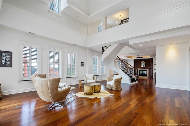 living room featuring ornamental molding, a towering ceiling, and hardwood / wood-style floors