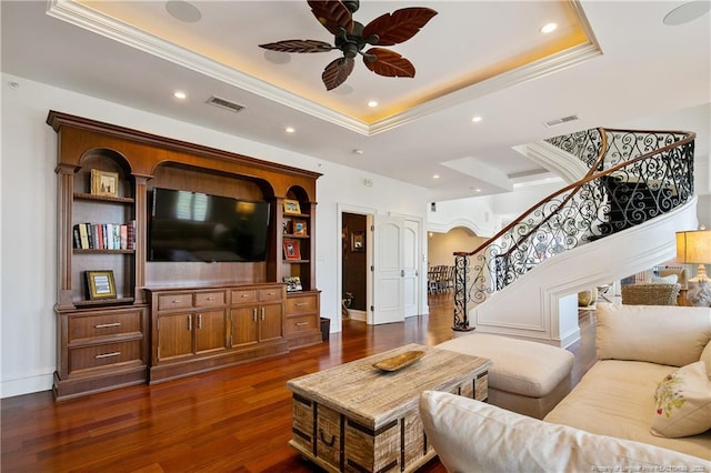 living room with ceiling fan, a raised ceiling, crown molding, and dark hardwood / wood-style flooring