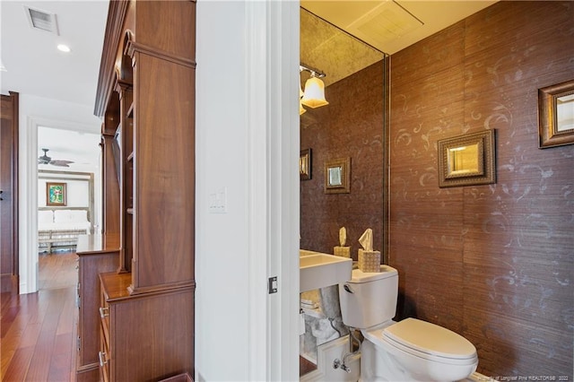 bathroom featuring hardwood / wood-style flooring, ceiling fan, and toilet