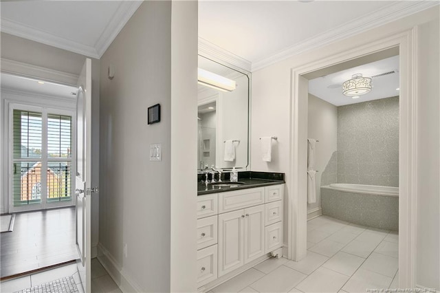 bathroom featuring a tub, vanity, crown molding, and tile patterned floors