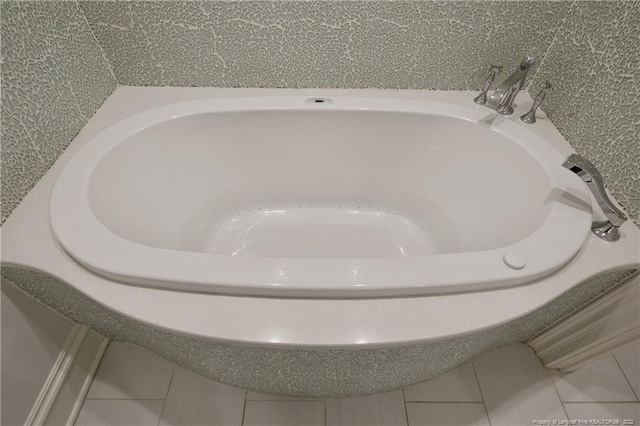 interior details with a tub to relax in and tile patterned floors