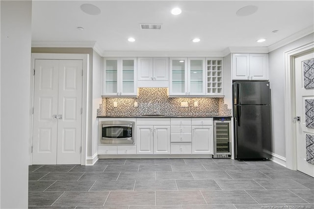 kitchen featuring tasteful backsplash, beverage cooler, stainless steel microwave, black fridge, and white cabinets