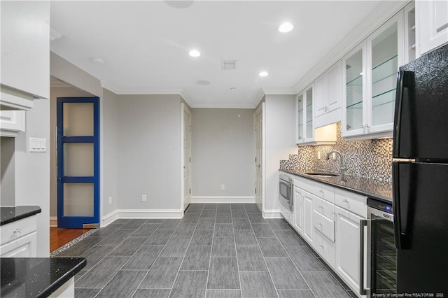 kitchen featuring beverage cooler, stainless steel microwave, black fridge, sink, and white cabinets