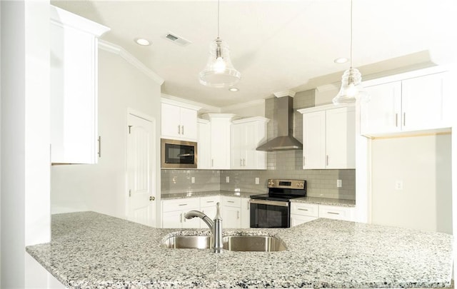 kitchen with hanging light fixtures, stainless steel appliances, wall chimney range hood, and white cabinets
