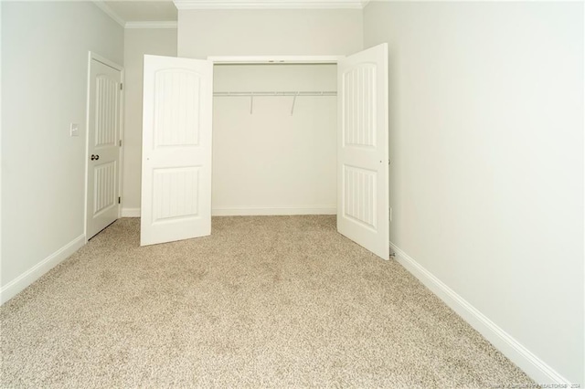 unfurnished bedroom with ornamental molding, light colored carpet, and a closet
