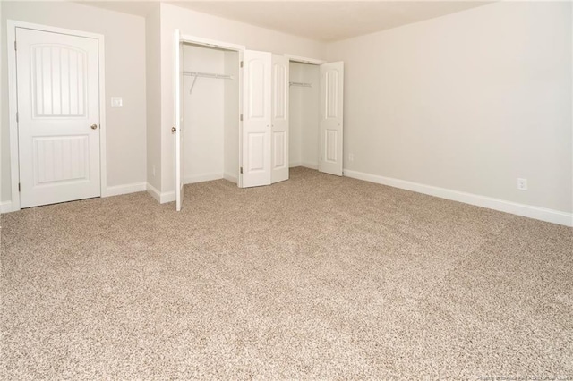 unfurnished bedroom with light colored carpet and multiple closets