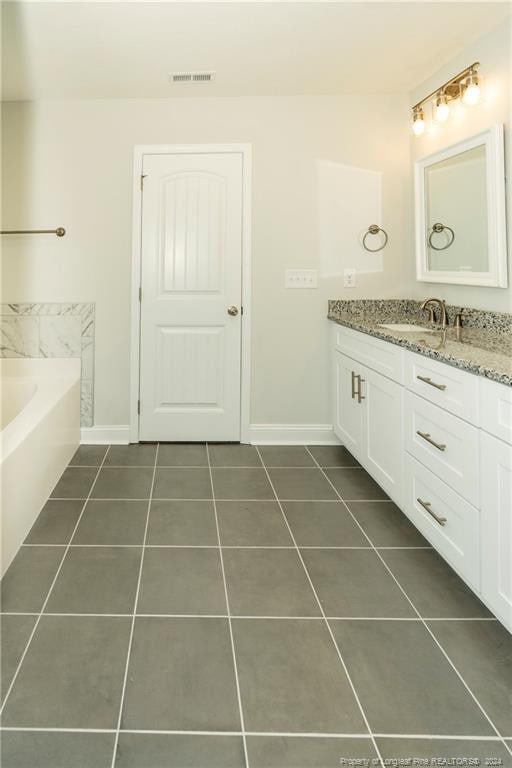 bathroom featuring a washtub, tile flooring, and vanity