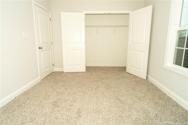 unfurnished bedroom with light carpet and a closet