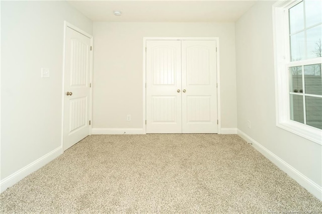 unfurnished bedroom with light colored carpet and a closet