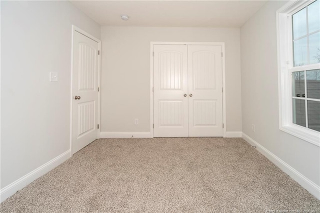 unfurnished bedroom featuring light colored carpet and a closet