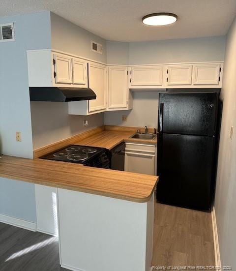 kitchen featuring kitchen peninsula, black appliances, wood-type flooring, sink, and white cabinetry