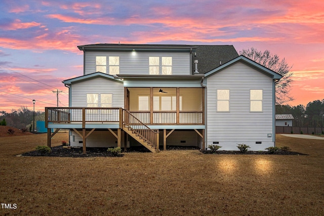 back house at dusk with a lawn and ceiling fan