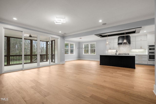 unfurnished living room with crown molding and light hardwood / wood-style floors