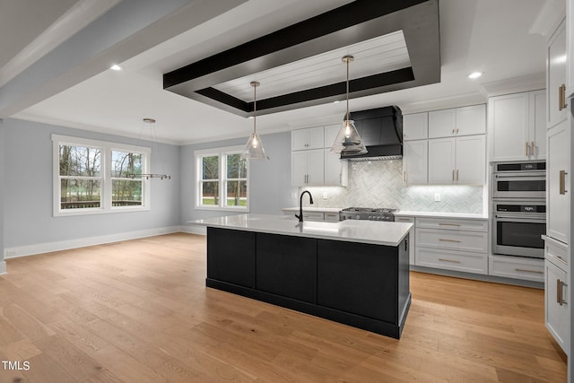 kitchen featuring light wood-type flooring, premium range hood, a raised ceiling, and double oven