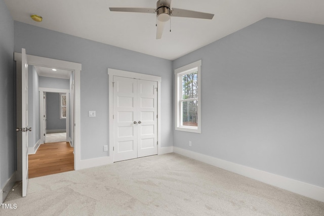 unfurnished bedroom with ceiling fan, a closet, lofted ceiling, and light carpet