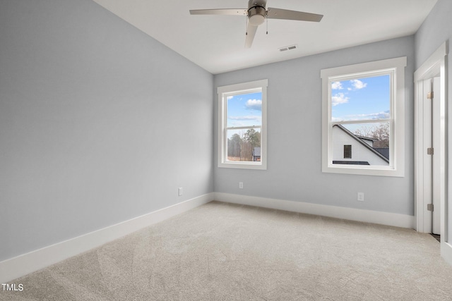 carpeted spare room featuring ceiling fan and a healthy amount of sunlight