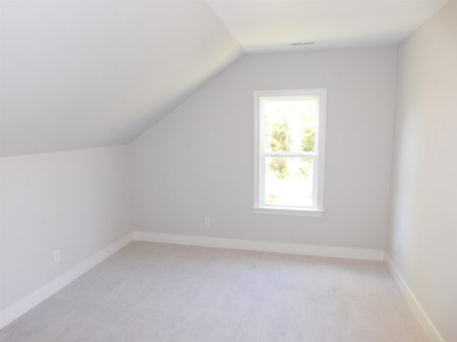 bonus room with vaulted ceiling and light carpet