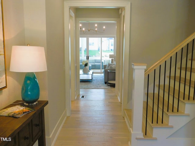 hallway featuring a notable chandelier and light hardwood / wood-style floors