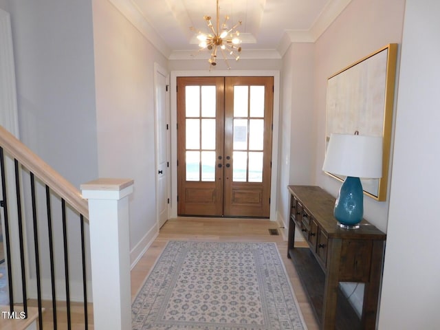 doorway to outside featuring french doors, crown molding, a notable chandelier, and light hardwood / wood-style flooring