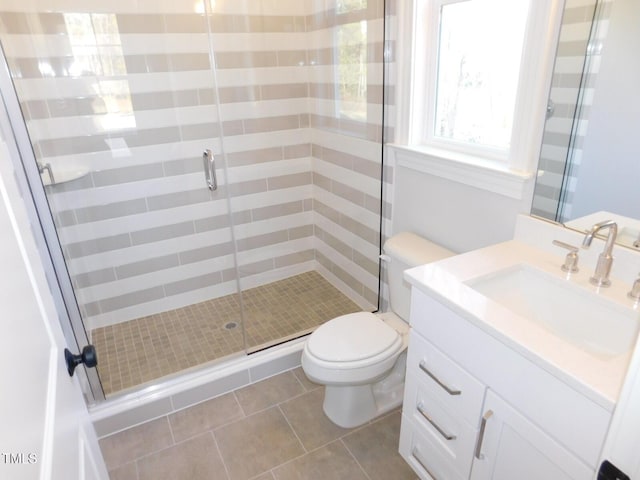 bathroom featuring tile patterned flooring, vanity, a shower with shower door, and toilet